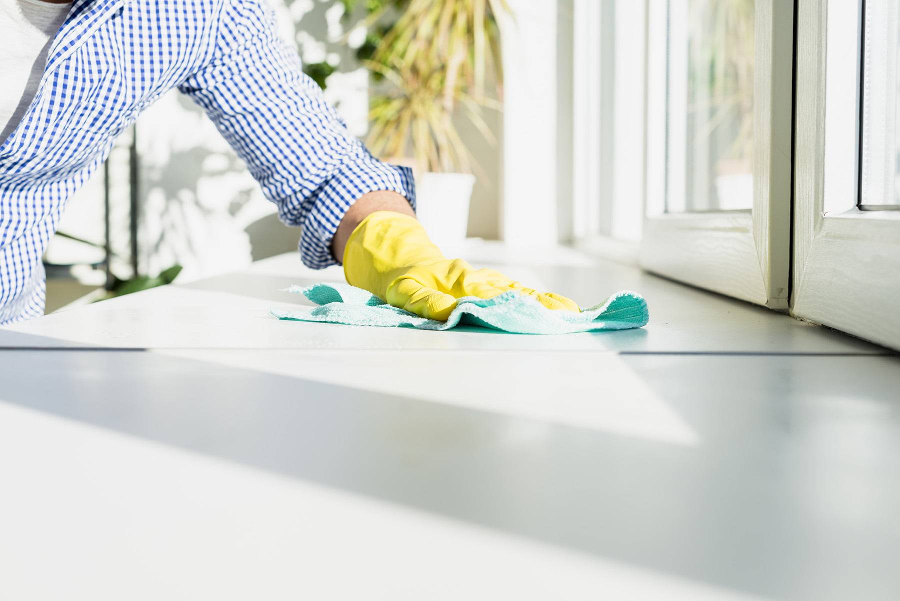 Man with a checkered shirt on cleaning a kitchen bench